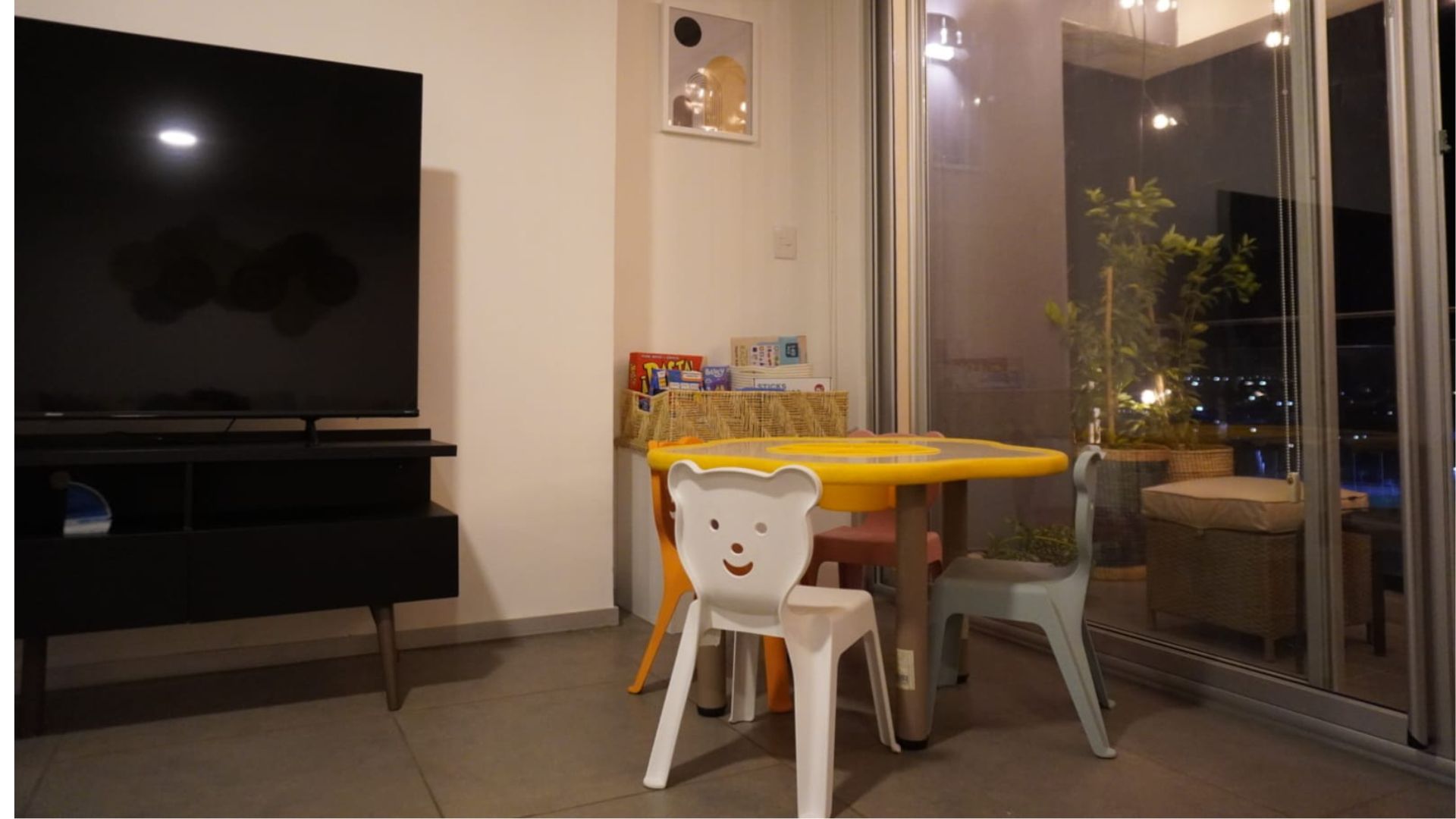 Área de juegos para niños dentro del departamento con mesa y libros